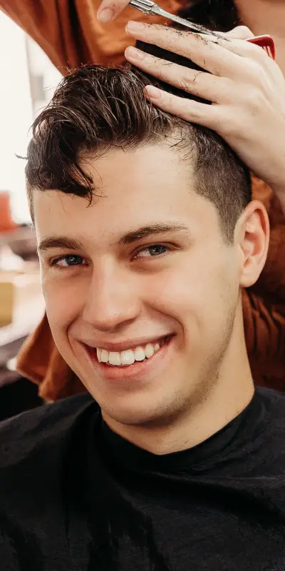 about section img A hairstylist trims the hair of a seated client, showcasing a modern salon setting with warm lighting and focused attention on the haircut.